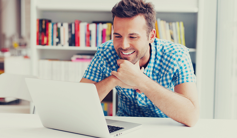 An image for a blog titled "12 Essential points to be considered while you are reopening your dental practice after lock down." showing a man smiling at a laptop on a white background.